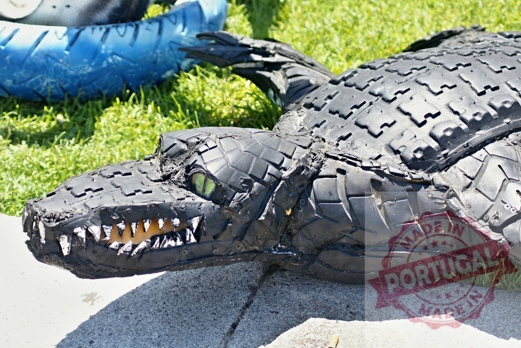 Crocodile tire sculpture representing recycling and creativity | Tire art crafting a crocodile sculpture with bright green eyes and sharp teeth - Realisiert mit Pictrs.com