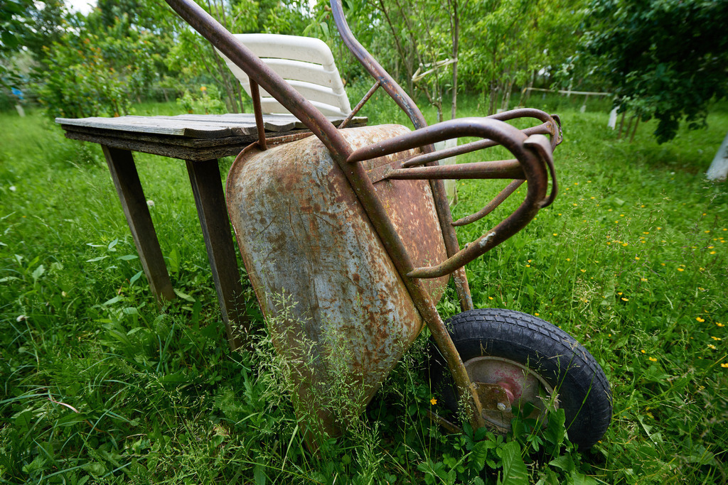 abgestellter rostiger Schubkarren im Garten | Austria - June 01, 2019: abgestellter rostiger Schubkarren im Garten. - Realisiert mit Pictrs.com