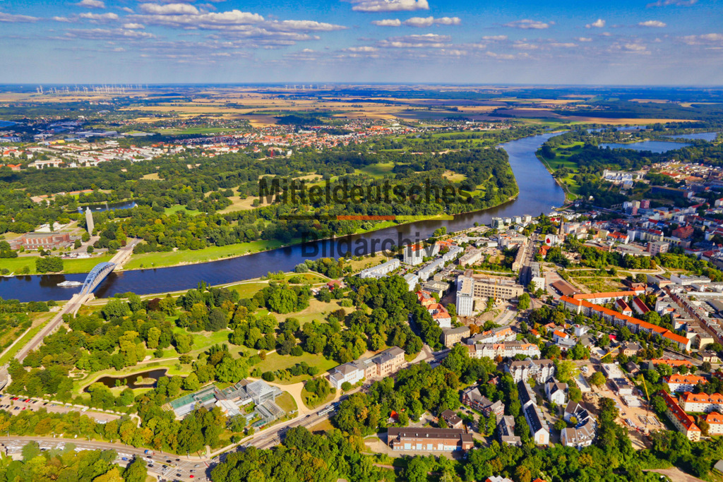 Magdeburg_Buckau_Lennepark_Gewächshaus_Elbe_Stadtpark_5206 | Buckau zählt zu den traditionsreichsten Stadtteilen Magdeburgs und war über viele Jahrzehnte ein bedeutender Industrie- und Maschinenbaustandort. Die Lage direkt an der Elbe sowie der Blick auf den gegenüberliegenden Stadtpark Rotehorn verdeutlichen die enge Verbindung zwischen urbanem Leben, Flusslandschaft und Erholungsraum. Aus der Luft wird die besondere Lage Buckaus zwischen historischer Bebauung, modernen Wohnquartieren und den weitläufigen Elbauen eindrucksvoll sichtbar. - Realisiert mit Pictrs.com