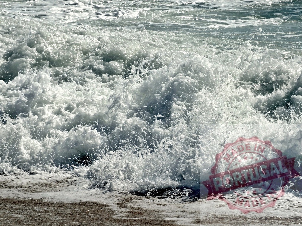 Ocean wave crashing on beach creating foam | Ocean wave breaking on a sandy shore, creating white foam and splashing water - Realisiert mit Pictrs.com