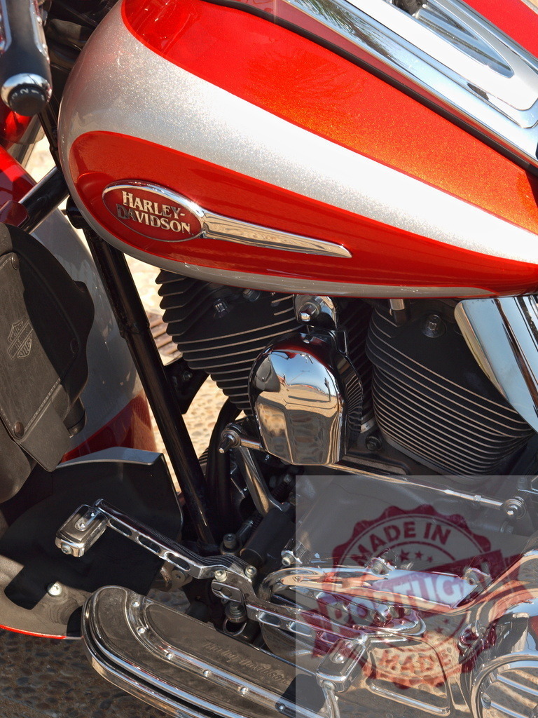 Harley-Davidson cruiser motorcycle engine and gas tank | Red and silver Harley-Davidson gas tank and chrome engine components on a cruiser motorcycle - Realized with Pictrs.com