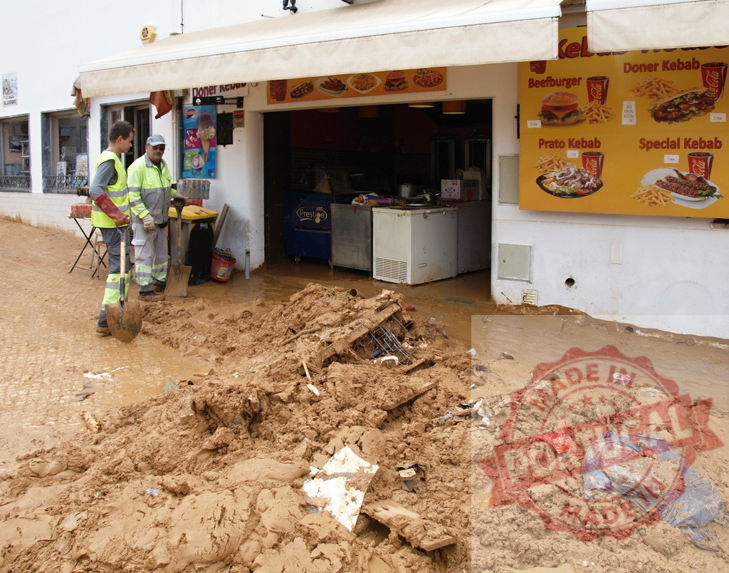 Workers cleaning mud and debris after street flood | Albufeira Flood - discruction by weather problems Workers cleaning muddy street in front of a shop after a natural disaster - Realisiert mit Pictrs.com