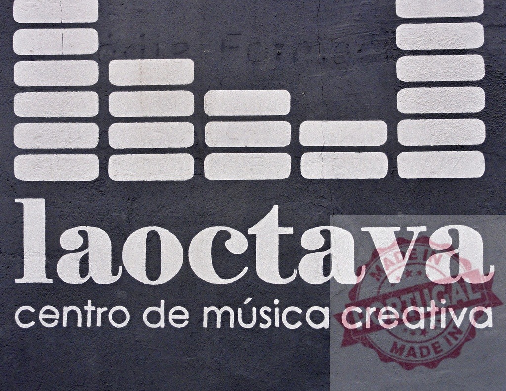 La Octava creative music center logo on wall | La Octava centro de música creativa sign with graphic equalizer bars on a textured wall - Realisiert mit Pictrs.com