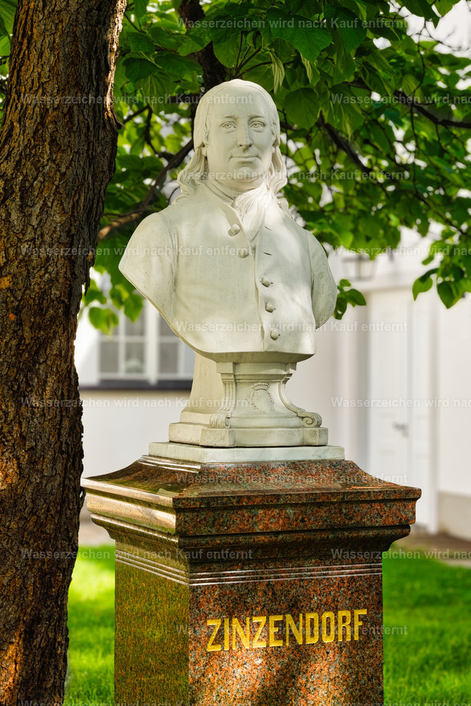 Herrnhut - Zinzendorfbüste im Kirchgarten | Büste von Nikolaus Ludwig von Zinzendorf vor dem historischen Kirchsaal in Herrnhut – ein eindrucksvolles Motiv zur Geschichte und Gründung der Herrnhuter Brüdergemeine. Herrnhut ist eine Stadt im sächsischen Landkreis Görlitz in der Oberlausitz. Zentral zwischen den Städten Löbau und Zittau gelegen, ist sie als Gründungsort der Herrnhuter Brüdergemeine, durch die Produktion der Herrnhuter Sterne und internationale Missionsarbeit bekannt. - Realisiert mit Pictrs.com
