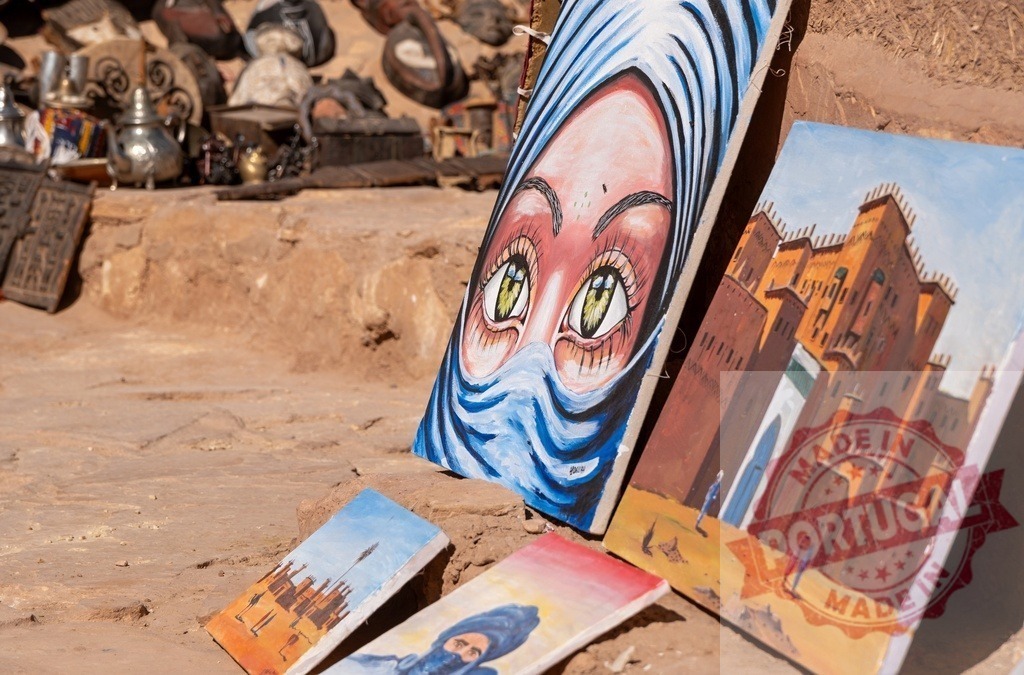 Naive paintings depicting berber woman and kasbah in Morocco | Colorful naive paintings depicting a berber woman and a kasbah exposed on the ground in a Moroccan market - Realized with Pictrs.com