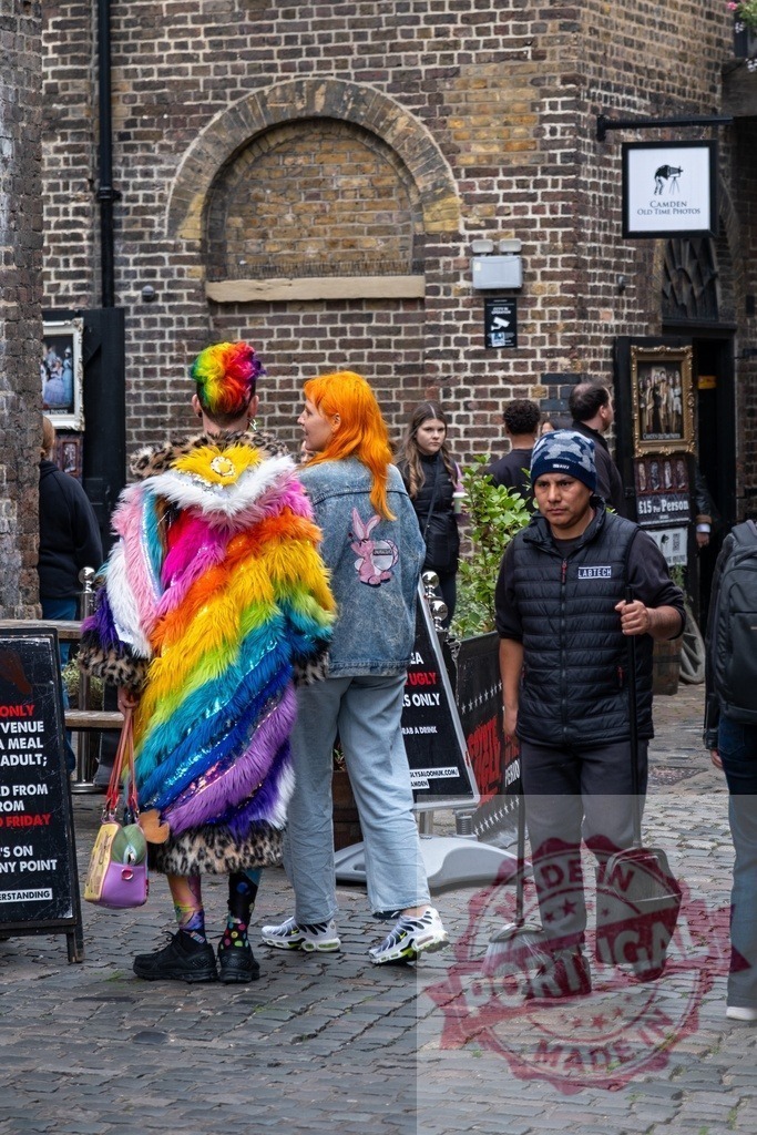 Camden Market style with colorful rainbow coat | People walking on a cobbled street in Camden Market, a man sweeping the street - Realized with Pictrs.com