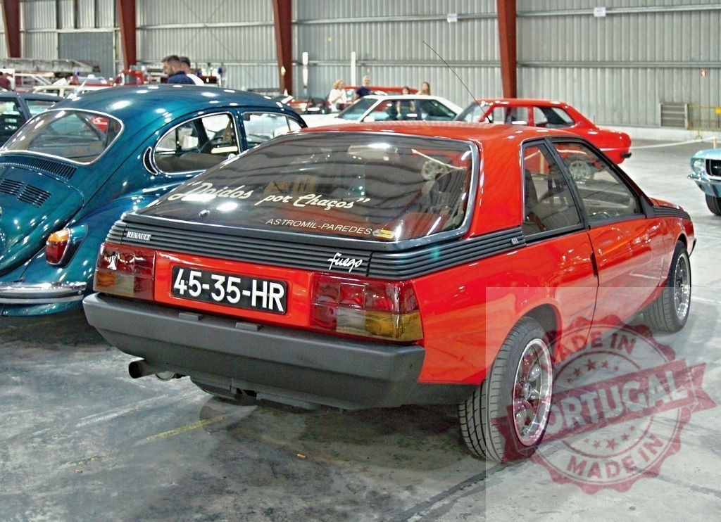 Red Renault Fuego parked in exhibition hall with Volkswagen Beetle nearby | Shiny red Renault Fuego with Spanish license plate parked in exhibition hall with Volkswagen Beetle nearby - Realisiert mit Pictrs.com