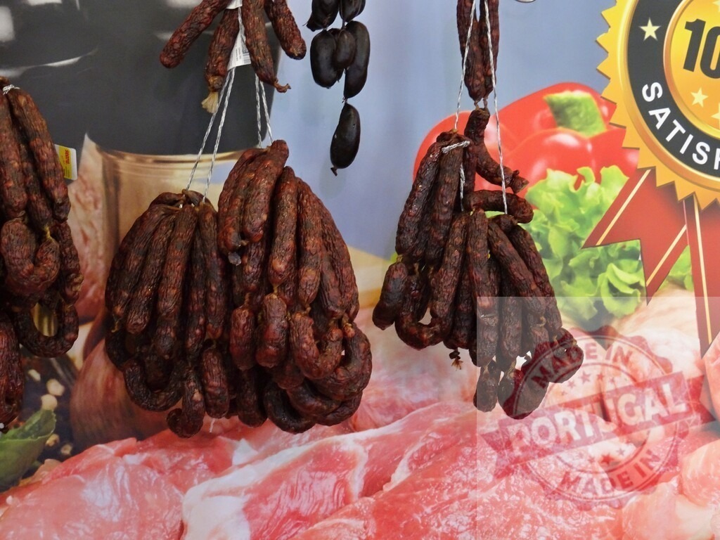 Smoked sausages hanging at market stall | Dried sausages hanging in bundles for sale at a butcher's stand - Realisiert mit Pictrs.com