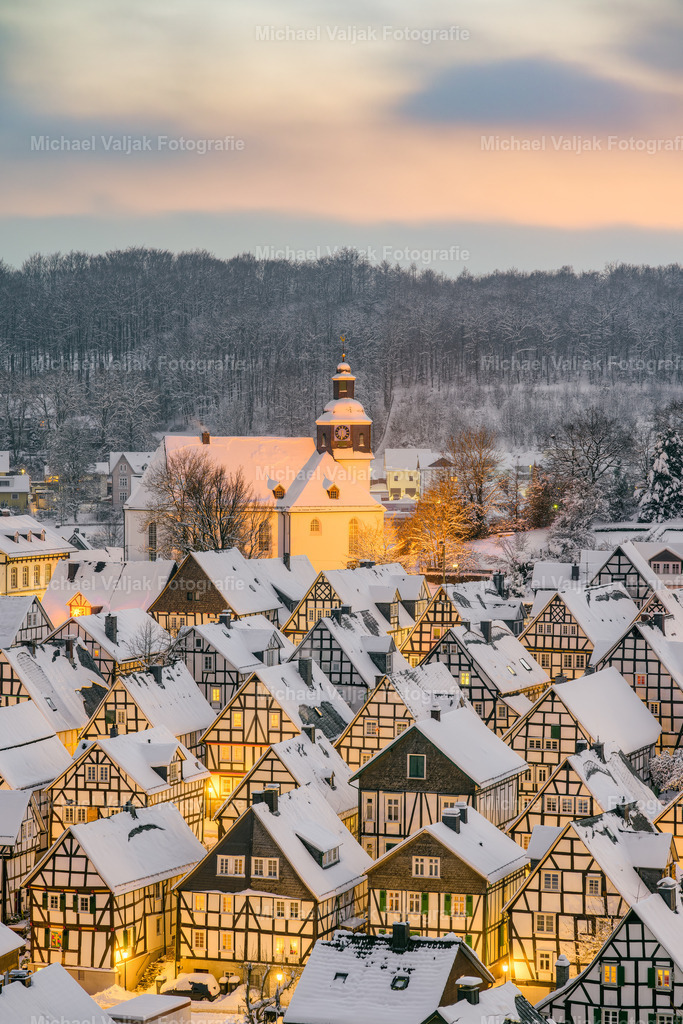 Freudenberg im Siegerland an einem Winterabend | Freudenberg ist eine malerische Stadt im Süden von Nordrhein-Westfalen, die für ihre historische Altstadt bekannt ist. An einem Winterabend erstrahlt die Stadt in einem besonderen Licht, das die Fachwerkhäuser und die Kirche hervorhebt. Die Luft ist kalt und klar, und man kann den Schnee unter den Füßen knirschen hören. Freudenberg ist ein Ort, der Tradition und Moderne verbindet, und an einem Winterabend kann man das besonders spüren. - Realisiert mit Pictrs.com
