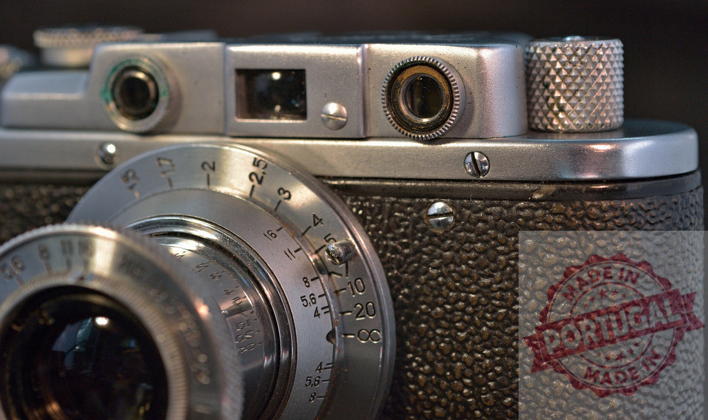 Vintage analog camera close-up with focusing lens | Vintage analog rangefinder camera body with metallic lens and film advance knob detail - Realisiert mit Pictrs.com