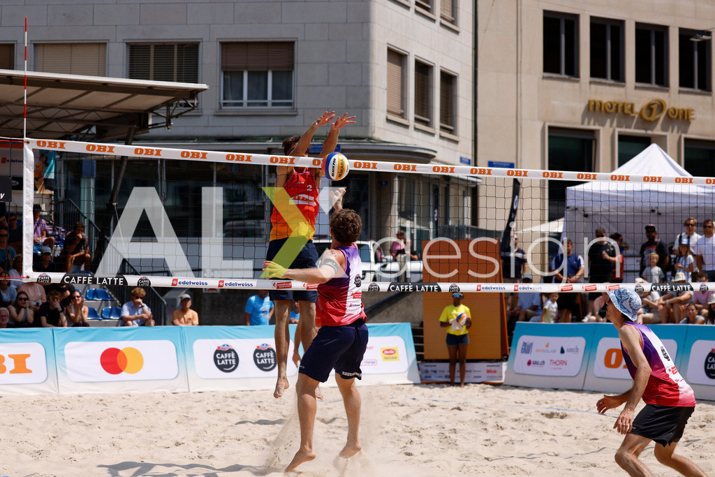 Obi BeachTour 2026 - Basel | BASEL, SWITZERLAND - JULY 19: YVES HAUSSENER (SUI) attack / spike against LUC EMANUEL FLÜCKIGER (SUI) block during the Obi BeachTour 2026 match between DILLIER / FLÜCKIGER (SUI) and HAGENBUCH / HAUSSENER (SUI) at Barfüsserplatz on July 19, 2026 in Basel, Switzerland. - Realisiert mit Pictrs.com