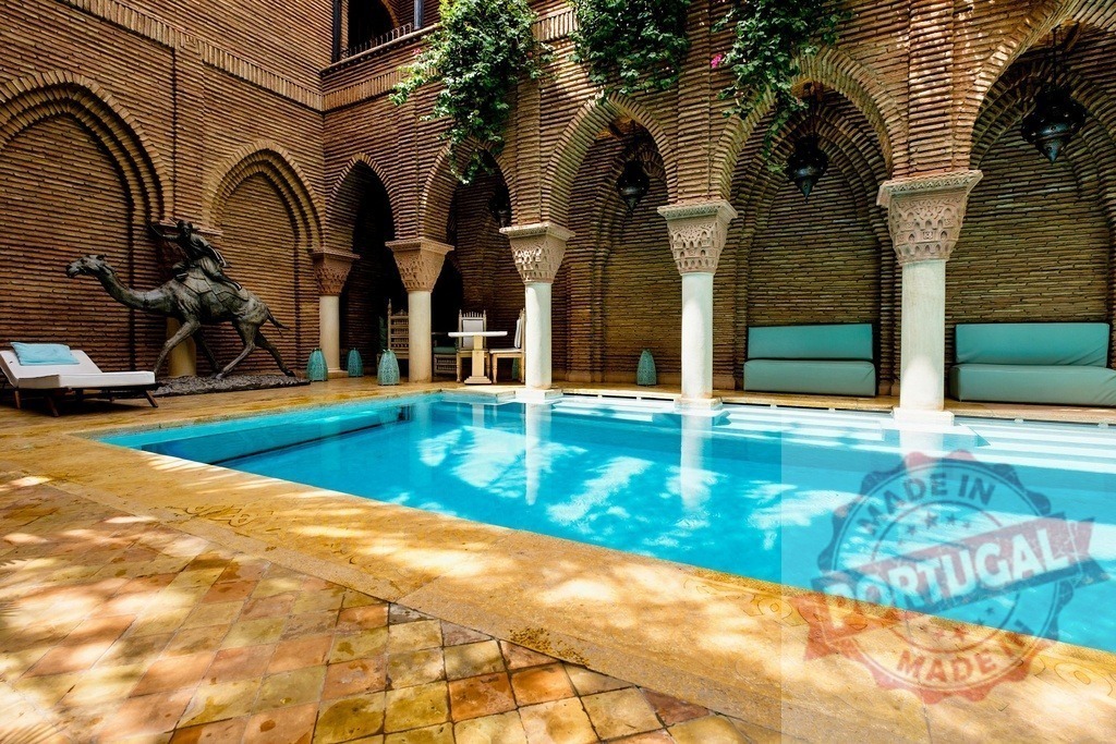 Moroccan riad courtyard featuring a swimming pool and arches | Moroccan riad courtyard featuring a blue swimming pool, brick arches, and a camel statue - Realisiert mit Pictrs.com