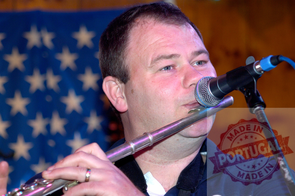 Musician playing flute in concert with American flag | Man playing flute into a microphone during a musical performance with an American flag in the background - Realisiert mit Pictrs.com