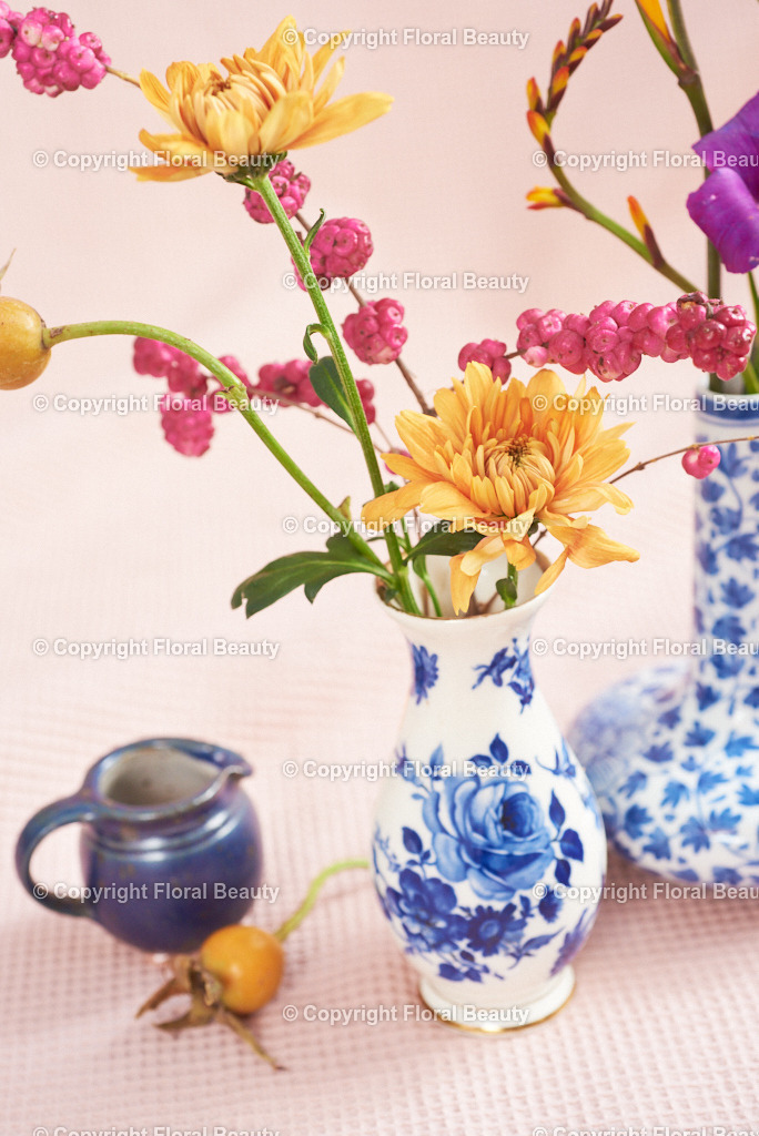 Blau-weiße Vasen mit Montbretien auf rosa | zwei kleine blau-weiße Vasen mit orangen Montbretien auf rosa Untergrund als Druck als Wandbild - Realisiert mit Pictrs.com