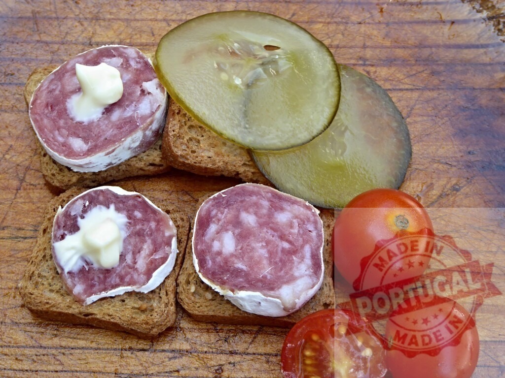 Salami appetizer on toast with pickles and tomatoes | Salami and mayonnaise on toast slices with cucumber pickles and fresh tomatoes on a rustic wooden board - Realisiert mit Pictrs.com
