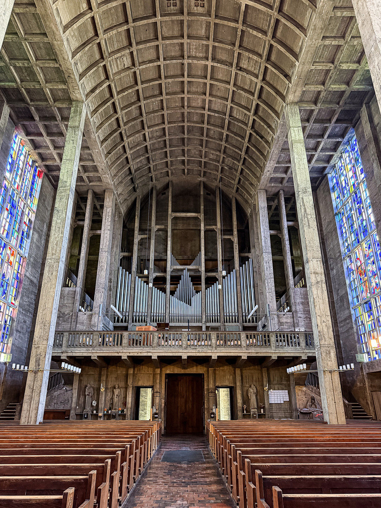 Sound of Concrete – Monumentale Orgel der Antoniuskirche Basel Wandbild & Fine Art Print | Wo monumentaler Brutalismus auf den Klang der Ewigkeit trifft. Diese High-End-Fotokunst zeigt die perfekt symmetrische Perspektive auf die gewaltige Orgel der historischen Antoniuskirche in Basel. Die eiskalten, metallischen Linien der Orgelpfeifen fügen sich meisterhaft in das ikonische Raster des rohen Sichtbetons ein, flankiert vom farbgewaltigen Leuchten der Buntglasfenster. Ein absolut avantgardistisches Statement-Piece für moderne Lofts, anspruchsvolle Geschäftsräume oder minimalistische Design-Wände.Material-Empfehlung: Für diese kontrastreiche, architektonische Symmetrie empfehle ich ganz klar den Druck hinter glänzendem Acrylglas. Das Acrylglas verleiht dem Metall der Orgelpfeifen eine spektakuläre Dreidimensionalität und bringt das farbige Licht der Fenster magisch zum Leuchten.Bringen Sie zeitlose Schweizer Architekturgeschichte an Ihre Wände. Sichern Sie sich dieses exklusive Wandbild modern jetzt für Ihre private Galerie.[Archiv-Nr. #0121] - Realisiert mit Pictrs.com