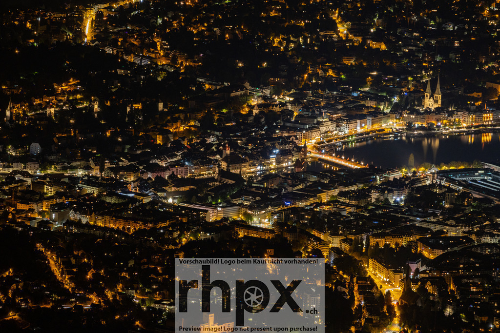 Luzern bei Nacht – Blick auf die Stadt | Der Blick von oben zeigt Luzern bei Nacht. Die Stadtlichter spiegeln sich auf der Reuss und zeigen das charakteristische Stadtbild mit der Kapellbrücke und dem Seeufer. - Realisiert mit Pictrs.com