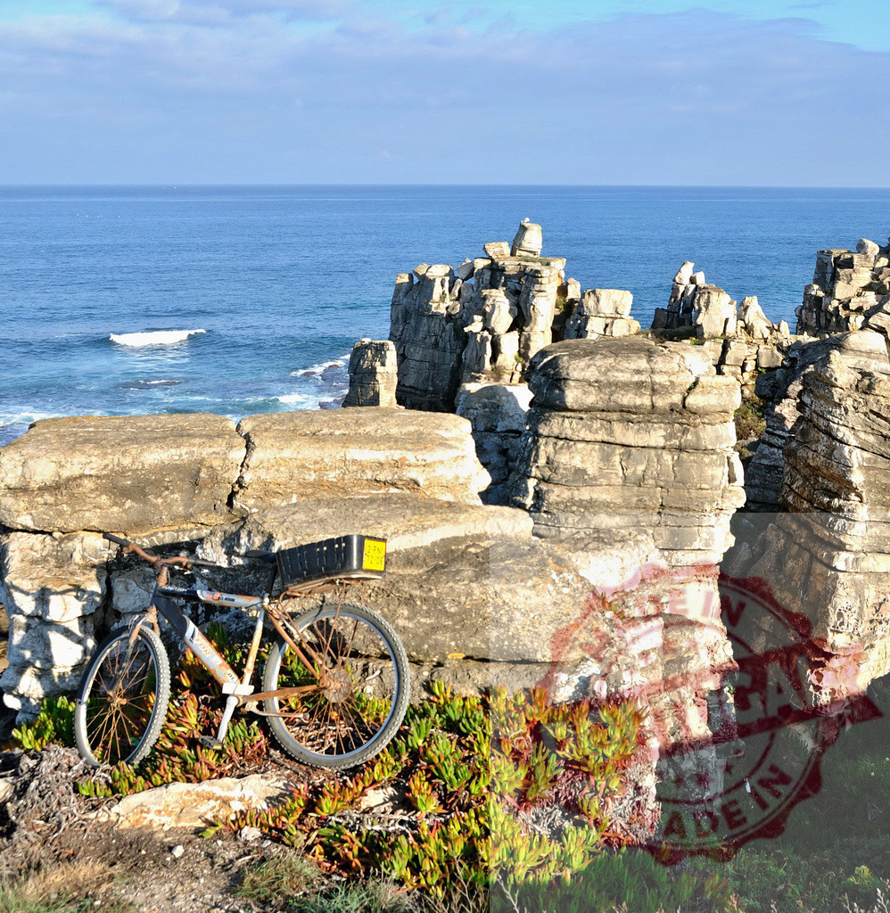 Old bicycle leaning on coastal rocks at Peniche. Centro - Portugal | Old bicycle finding shelter on the rocky coastline with the blue ocean in the background - Realisiert mit Pictrs.com