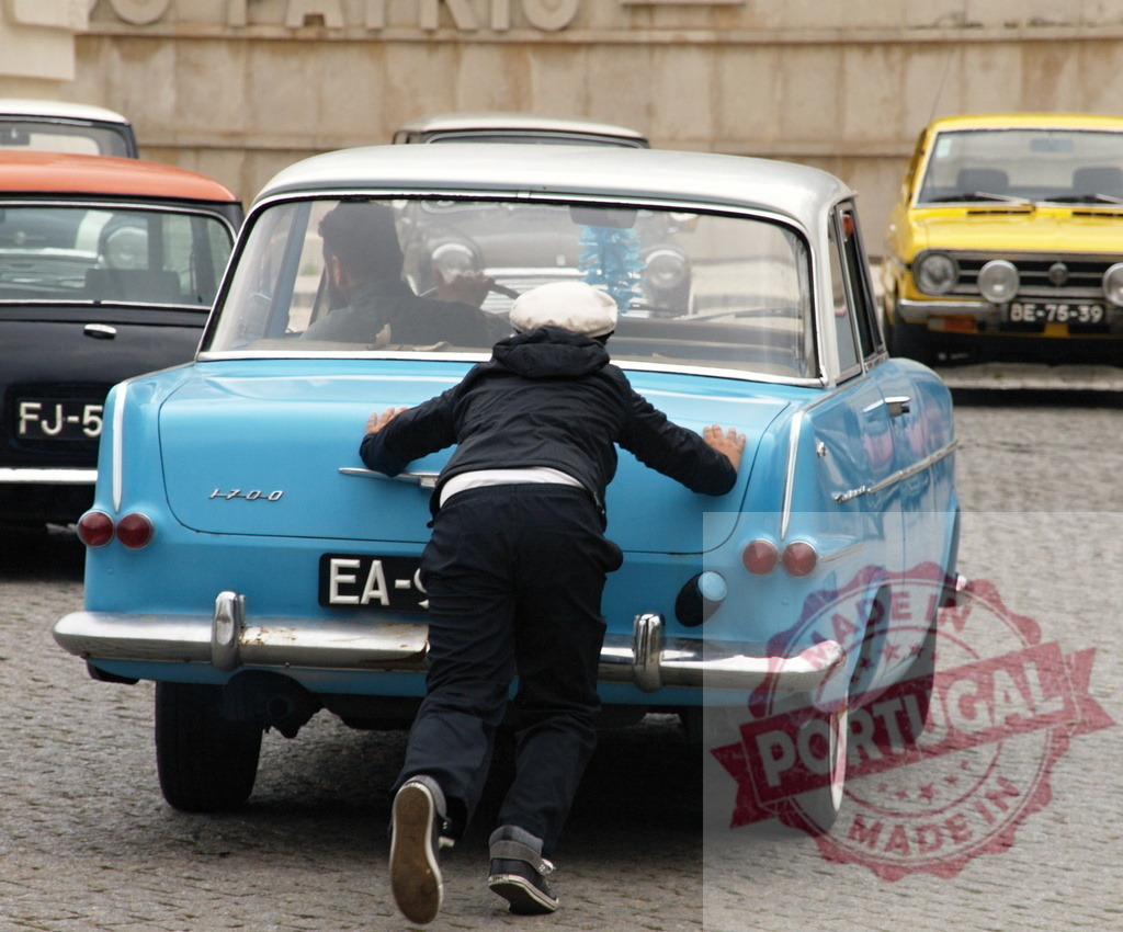 Man pushing vintage car on cobblestone street | Man pushing a light blue vintage car on a cobblestone street - Realized with Pictrs.com