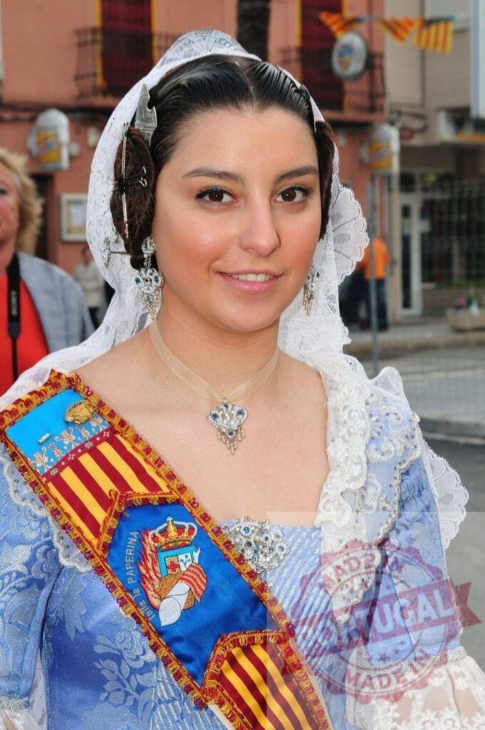 Smiling fallera in traditional costume celebrating Las Fallas | Smiling young woman wearing a traditional fallera dress, sash, and jewelry during a Spanish festival - Realized with Pictrs.com