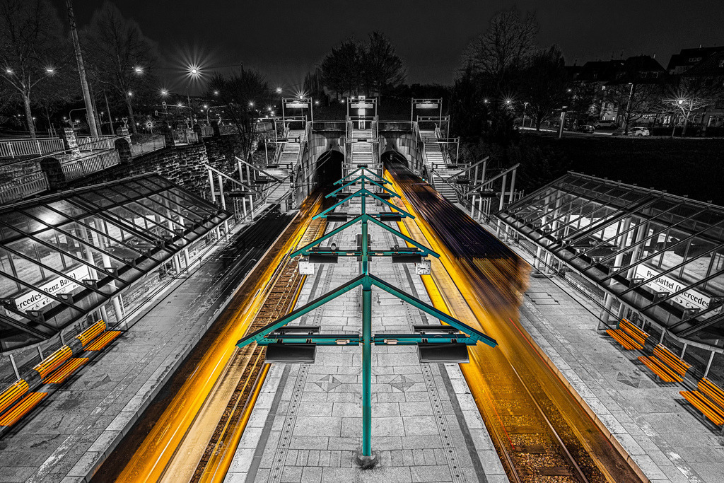 Bild der Stadtbahnhaltestelle Pragsattel in Stuttgart mit gelben Lichtspuren als selektive Schwarz-Weiß-Fotografie, Color Key | Das Bild zeigt eine Schwarzweiß-Aufnahme der Stadtbahnhaltestelle Pragsattel in Stuttgart mit gelben Lichtspuren von ein- und ausfahrenden Bahnen - Realisiert mit Pictrs.com