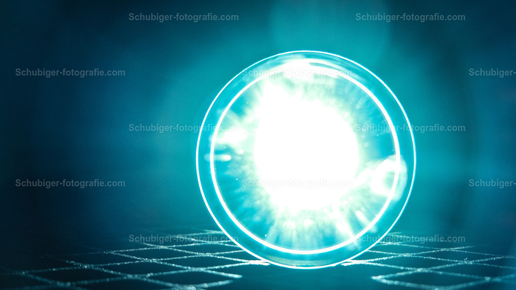 das Licht | Glaskugel mit Licht im Hintergrund auf Metallgitter - Realisiert mit Pictrs.com
