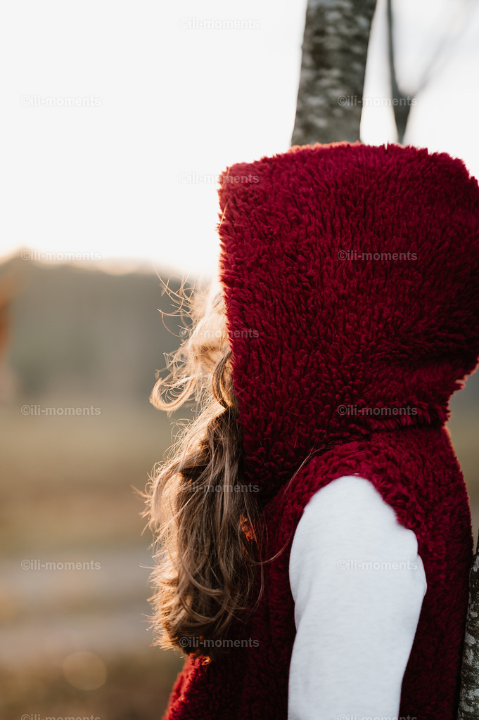 persönlicher Sonnenaufgang | Ein langhaariges Mädchen mit Kapuze steht im warmen Licht der aufgehenden Sonne, das Gesicht verborgen. Dieses Bild strahlt eine wohlige Energie und intime Ruhe aus – perfekt als Kunstdruck für besondere Raumstimmungen. - Realisiert mit Pictrs.com