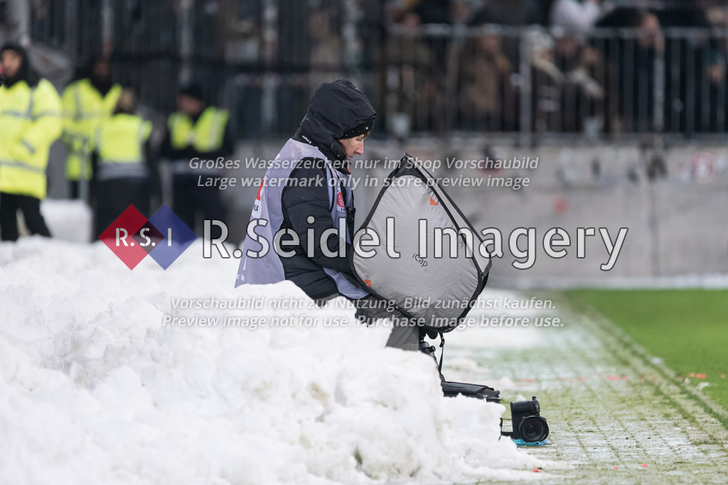 RS-1-148164 | Presse-Fotografin sitzt am Spielfeldrand zwischen Schneebergen mit abgeschirmtem Notebook auf dem Schoß.