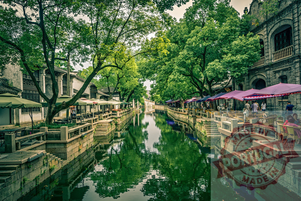 Ancient Wuzhen water town canal with outdoor cafes | Wuzhen water town canal with traditional buildings, cafes, trees, and reflections on the water - Realisiert mit Pictrs.com