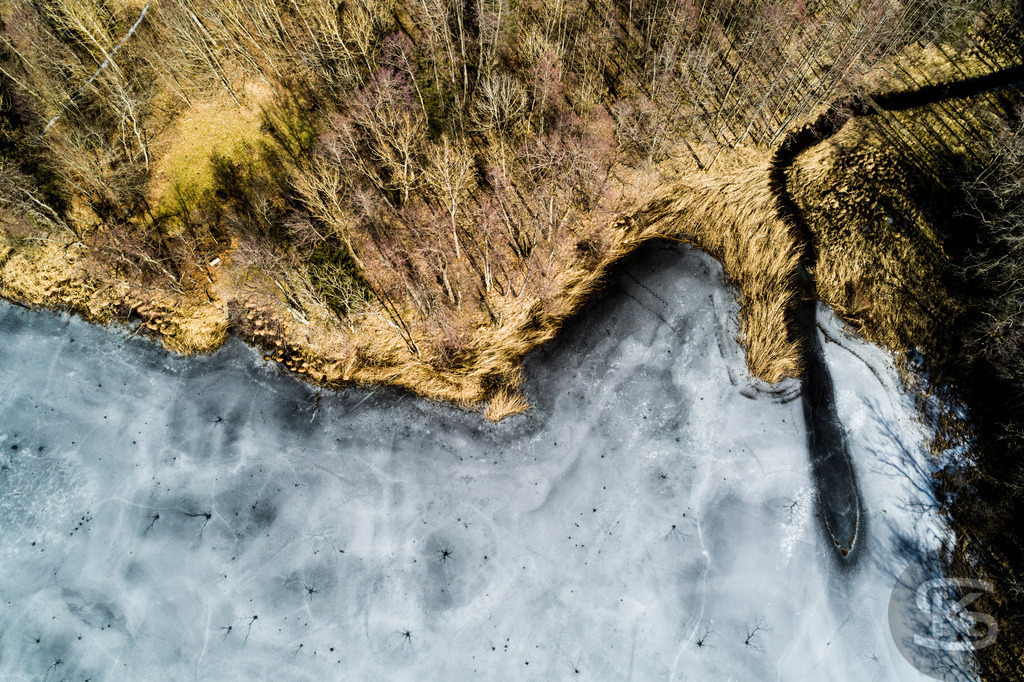 Zugefrorener See im Allgäu – Drohnenaufnahme von Eisstrukturen am Ufer | Beeindruckende Luftaufnahme eines vollständig zugefrorenen Sees im Allgäu. Die Drohnenfotografie zeigt faszinierende Eisstrukturen, Uferbereiche und natürliche Wintermuster aus der Vogelperspektive – einzigartige Winterlandschaft von oben. - Realisiert mit Pictrs.com