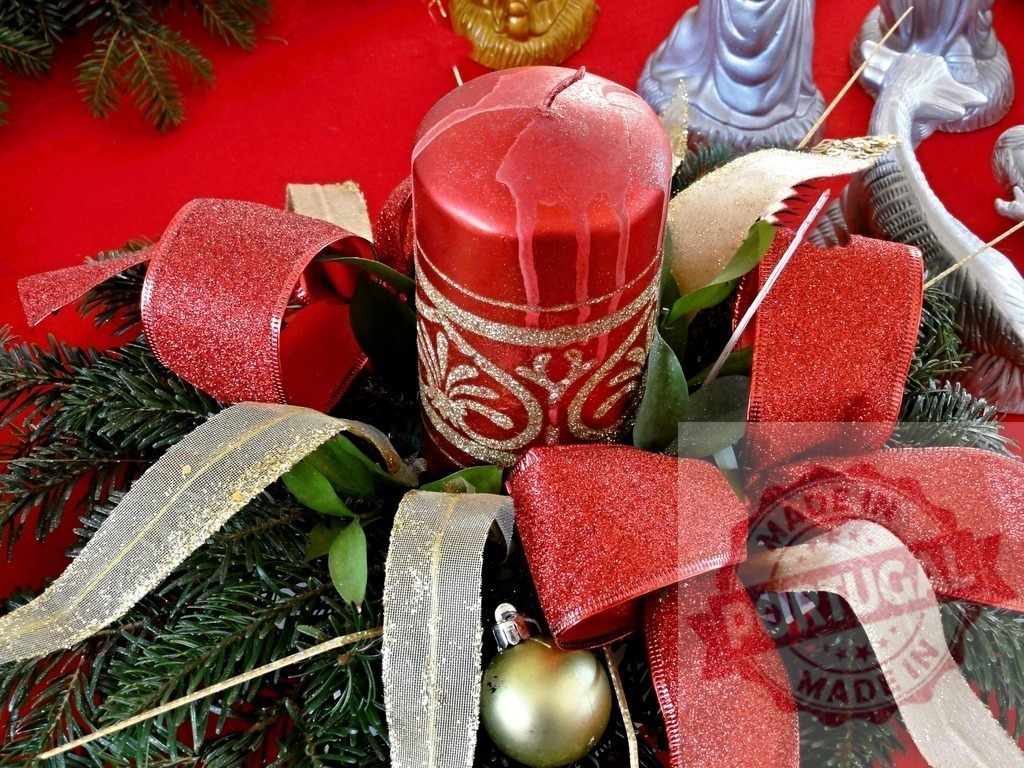 Red christmas candle centerpiece decorating a festive table | Christmas centerpiece with red candle, ribbons, bauble and fir branches on red background - Realized with Pictrs.com