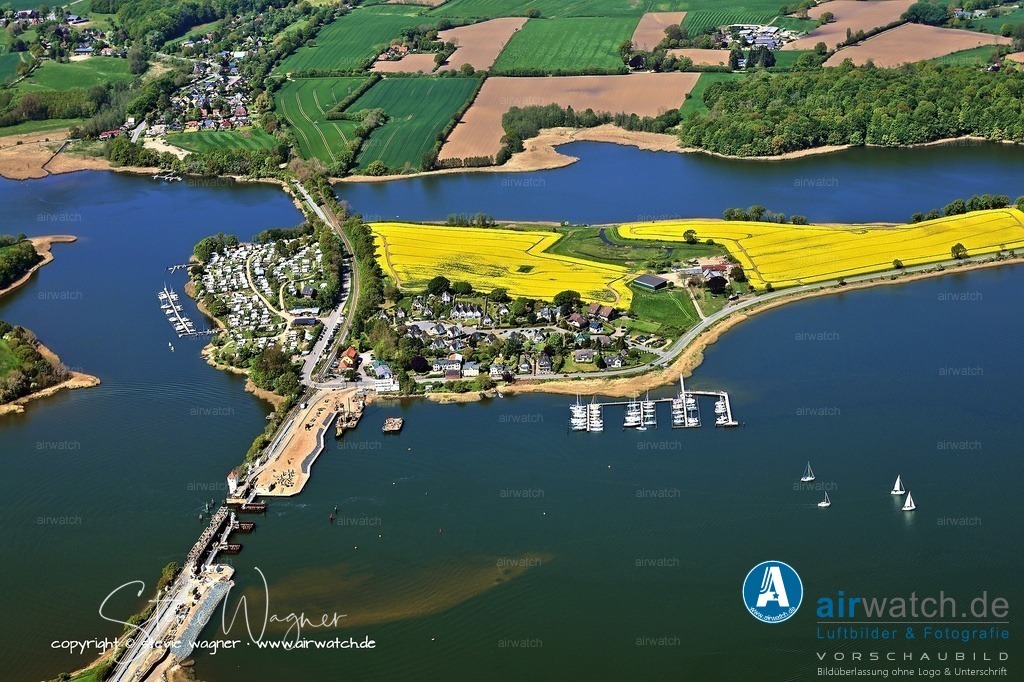 Luftbild Ostseefjord Schlei, Boren-Lindaunis Schleibrücke, Campingplatz Lindaunis, Sportboothafen Lindaunis | Lindaunisbrücke: Die Lindaunisbrücke, eine 1927 erbaute Klappbrücke, ist für den Straßenverkehr, Radfahrer und Fußgänger geöffnet. Die Überquerung der Brücke ist für Fußgänger auf einem schmalen Seitenstreifen möglich, wobei bei gleichzeitiger Busfahrt Vorsicht geboten ist. Die Brücke wird regelmäßig für den Bootsverkehr geöffnet, was die Umgebung zu einem beliebten Beobachtungspunkt macht.