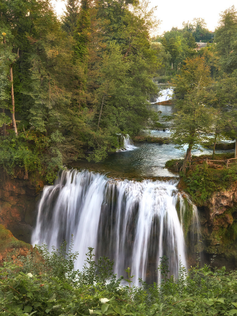 Romantische Wasserfalllandschaft, Kroatien | Das Foto entstand im schönen Ort Slunj in Kroatien, in der Nähe der Plitvicer Seen, an einem Sommerabend während einer Europa-Rundreise im Jahr 2023. Es zeigt den Fluss Korona, der in mehreren Armen durch das Dorf fließt und immer wieder über kleine oder größere Wasserfälle in die Tiefe stürzt.Unsere Empfehlung: Alu-Dibond oder Acrylglas - Realisiert mit Pictrs.com