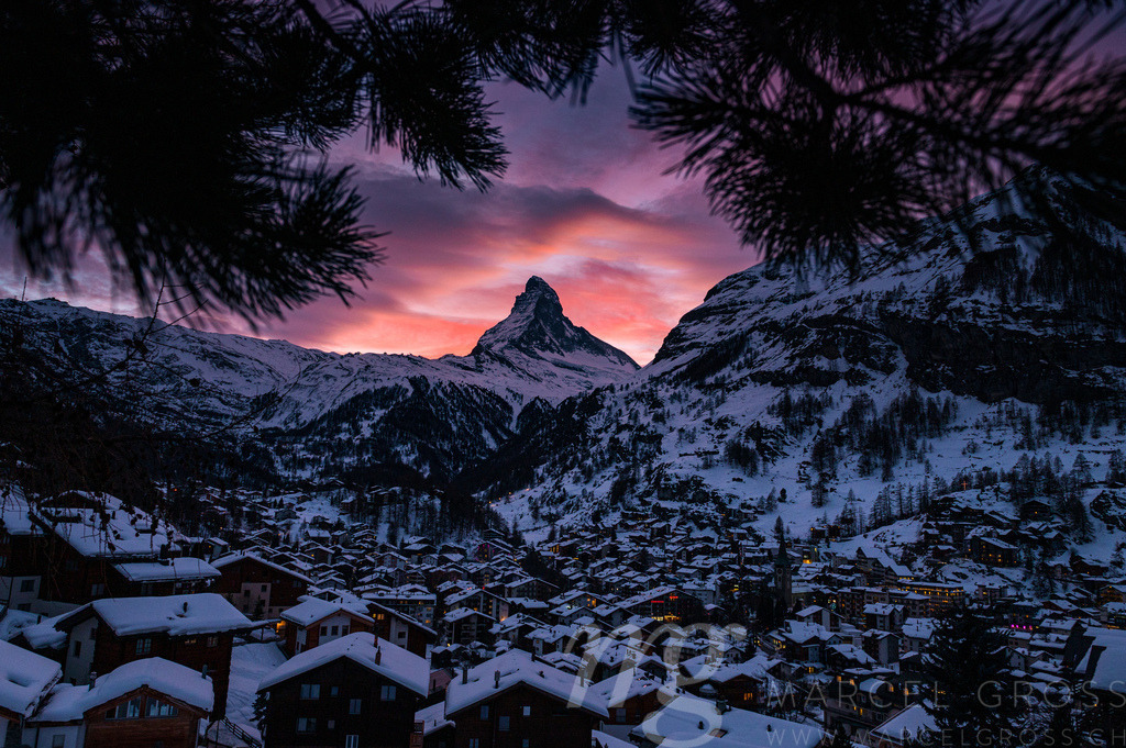 the alpine village of Zermatt in front of the Matterhorn at a wonderful sunset in the Alps of Switzerland. Framed by the branch of a fir tree | Die ideale Geschenkidee für Naturliebhaber. Naturbilder von Marcel Gross Photography für ihr Zuhause in den verschiedensten Formaten und Materialien. - Realisiert mit Pictrs.com