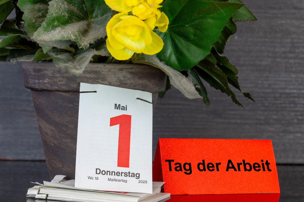 1. Mai, Tag der Arbeit | Maifeiertag: Das Blatt eines Abreißkalenders zeigt das Datum 1. Mai, daneben ein Zettel mit hinzugefügtem Text TAG DER ARBEIT - Realisiert mit Pictrs.com