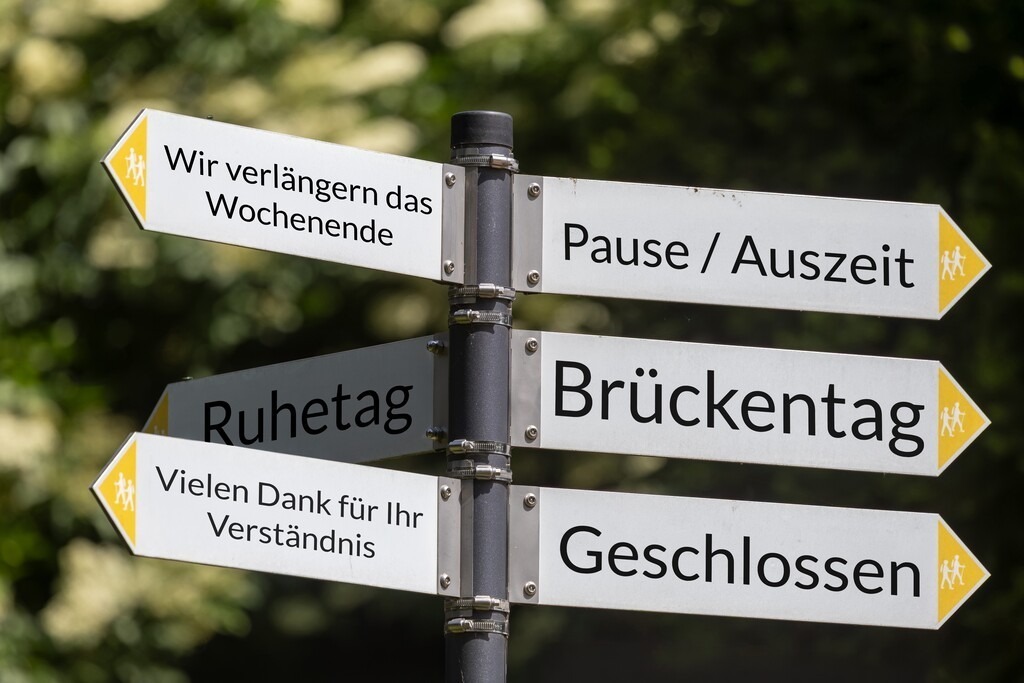 Brückentag geschlossen | (Photo montage) A hiking sign points in different directions with terms related to the topic of BRÜCKENTAG - Realisiert mit Pictrs.com
