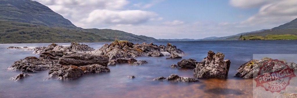 Scottish loch panorama with long exposure water and rocks | Rocks emerging from still water on a loch in the Scottish Highlands against distant mountains - Realisiert mit Pictrs.com