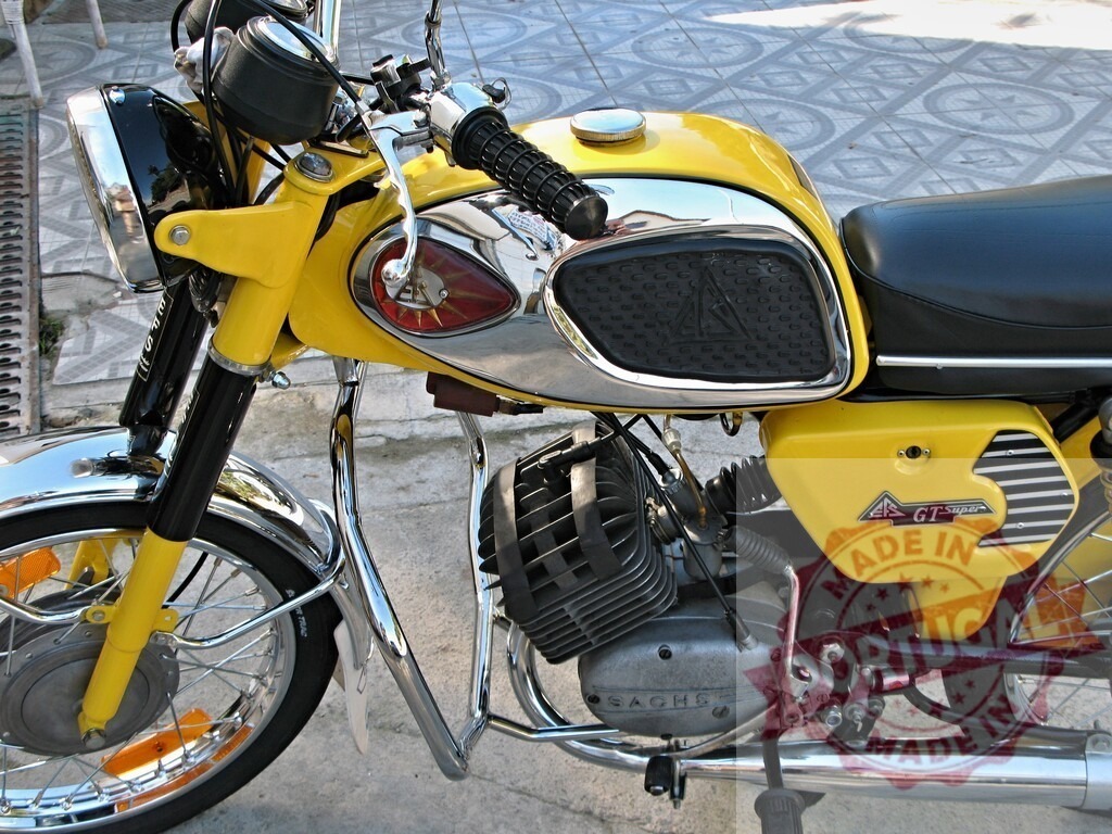 Yellow vintage motorcycle parked on a tiled floor, showcasing its Sachs engine | Gleaming chrome accents and vibrant yellow paint highlight this classic motorcycle with its Sachs engine, parked on a tiled floor - Realized with Pictrs.com