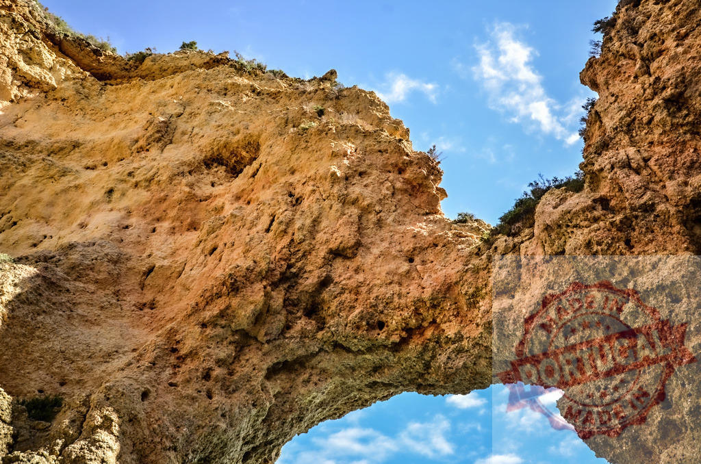 Ponta da Piedade natural rock arch bridge | Sandstone cliffs forming a natural bridge arch over blue sky - Realized with Pictrs.com