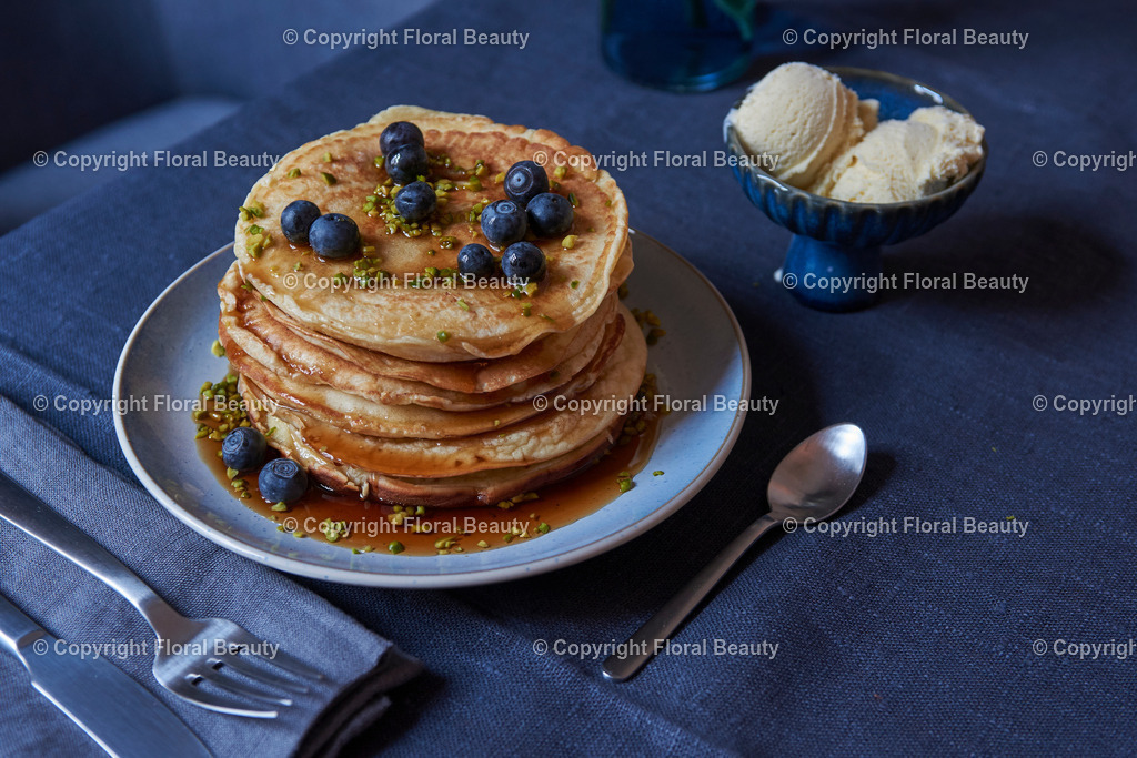 Pancakes mit Blaubeeren und Ahornsirup | gestapeltet Pancakes mit Blaubeeren, Ahornsirup und Pistazien mit Vanilleeis auf dunkler Tischdecke - Realisiert mit Pictrs.com