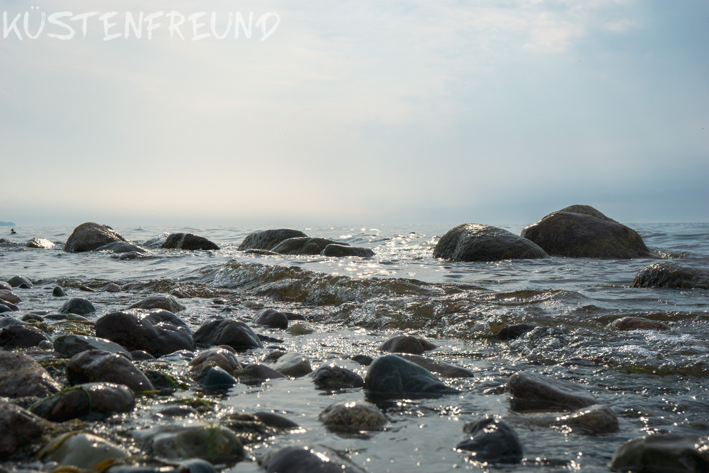 Spülsaum am Naturstrand mit leichten Wellen und Dunst // Ostseebild | Entdecke deine Lieblingslandschaft von der Küste – auf Ostsee Leinwand, Nordsee Leinwand, Alu Dibond oder Acrylglas, passend für jeden Geschmack und Raum.