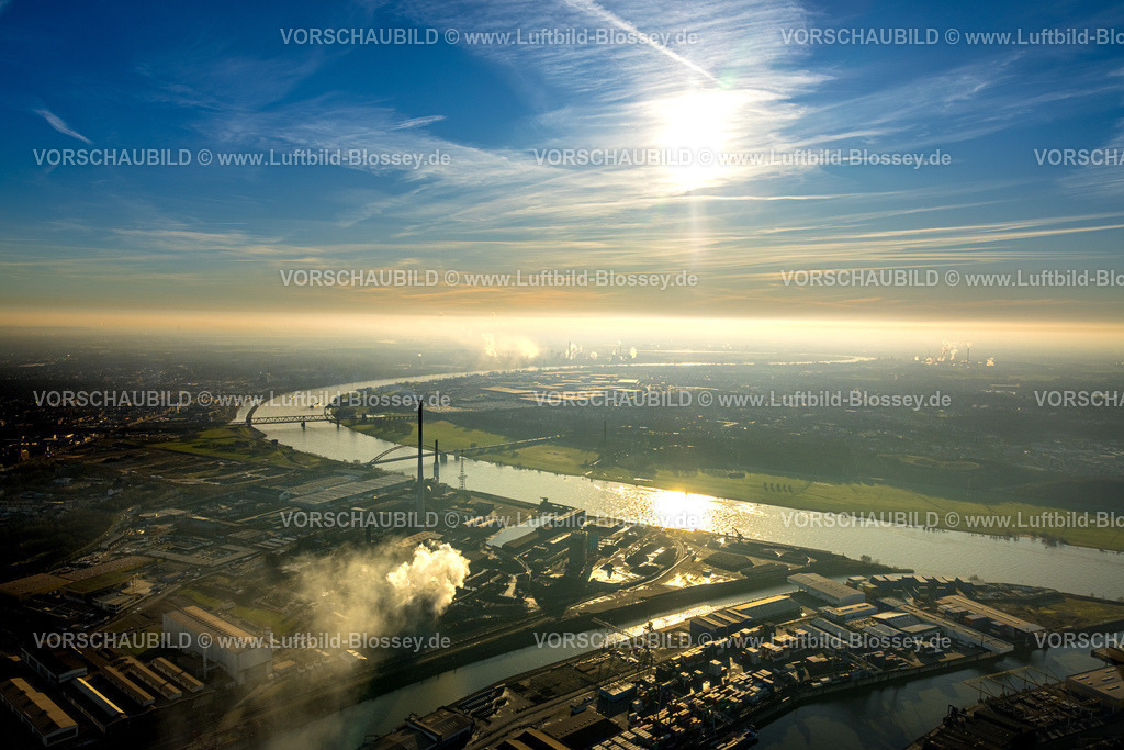 Duisburg241202411 | Luftbild, DK Recycling und Roheisen GmbH Werk, Rheinpark Baugelände mit Hochfelder Eisenbahnbrücke und Brücke der Solidarität über den Fluss Rhein, Rauchwolke im Gegenlicht und blauer Himmel mit Sonne, Hochfeld, Duisburg, Ruhrgebiet, Nordrhein-Westfalen, Deutschland