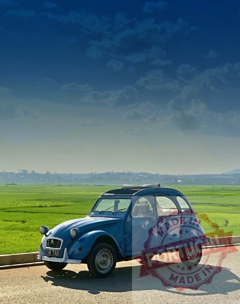 Blue Citroën 2CV parked near green rice fields under cloudy sky | Vintage blue Citroën 2CV parked on roadside near vast green rice fields under cloudy sky in Madagascar - Realized with Pictrs.com