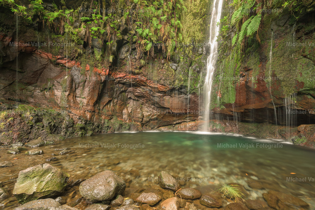 25 Fontes – Ein Wasserfall-Paradies auf Madeira | Die 25 Fontes, die „25 Quellen“, sind ein verstecktes Juwel im Laurisilva-Wald Madeiras. Tief eingebettet in die üppige Vegetation des UNESCO-Weltnaturerbes, entfaltet dieser Ort eine unvergleichliche natürliche Schönheit.Ein kleiner, klarer See liegt am Fuß von zahllosen herabstürzenden Wasserfällen, die wie silberne Fäden über moosbedeckte Felsen gleiten. Das sanfte Rauschen des Wassers erfüllt die Luft und vermischt sich mit den Geräuschen der Natur, während das Licht spielerisch durch die dichten Baumkronen fällt. Jeder Wasserfall trägt zur einzigartigen Atmosphäre bei und schafft ein Bild von Ruhe und Harmonie.Die Umgebung ist geprägt von einer Vielfalt an Farnen, Lorbeerbäumen und endemischen Pflanzen, die diesem Ort eine fast märchenhafte Stimmung verleihen. Die feuchte, kühle Luft des Waldes sorgt für eine erfrischende Stille, während die grüne Pracht die Besucher mit ihrer Vielfalt und Lebendigkeit beeindruckt.Der Weg zu den 25 Fontes ist ein Abenteuer für Naturliebhaber. Schmale Levada-Pfade, kleine Tunnel und die ständige Nähe zur Natur machen die Wanderung zu einem unvergesslichen Erlebnis. Nach der Anstrengung erwartet die Besucher ein Ort, der die Sinne beruhigt und die Seele berührt. - Realisiert mit Pictrs.com
