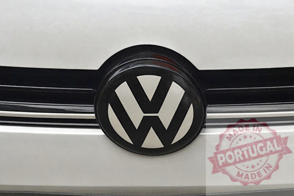 Volkswagen emblem on car grille representing automotive brand identity | Volkswagen logo on a white car grille, highlighting branding and vehicle design - Realisiert mit Pictrs.com