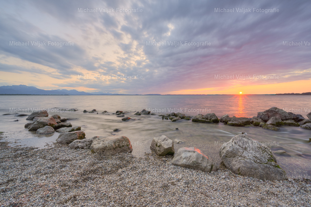 Abends am Strand in Chieming am Chiemsee | Der Chiemsee, oft als das "Bayerische Meer" bezeichnet, ist ein Ort der Ruhe und Schönheit. Ein Abend am Strand von Chieming bietet einen malerischen Blick auf das sanfte Glitzern des Wassers, während die Sonne hinter dem See untergeht. Es ist ein perfekter Moment, um die Seele baumeln zu lassen und die friedliche Atmosphäre zu genießen, die nur ein bayerischer See bieten kann. Die Kombination aus der natürlichen Schönheit des Sees und der entspannenden Umgebung macht Chieming zu einem idealen Ort für Erholungssuchende. - Realisiert mit Pictrs.com