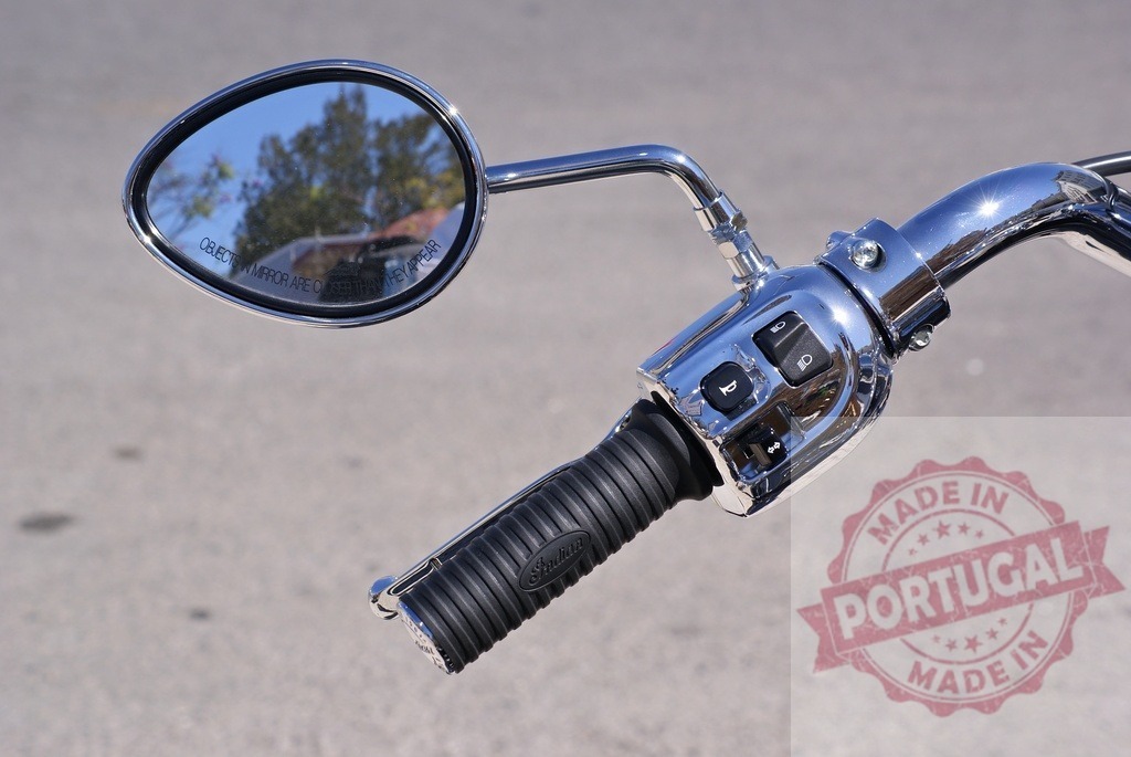 Motorcycle handlebar showing chrome mirror and controls | Motorcycle handlebar with chrome rearview mirror, throttle grip, and control switches on a sunny day - Realisiert mit Pictrs.com