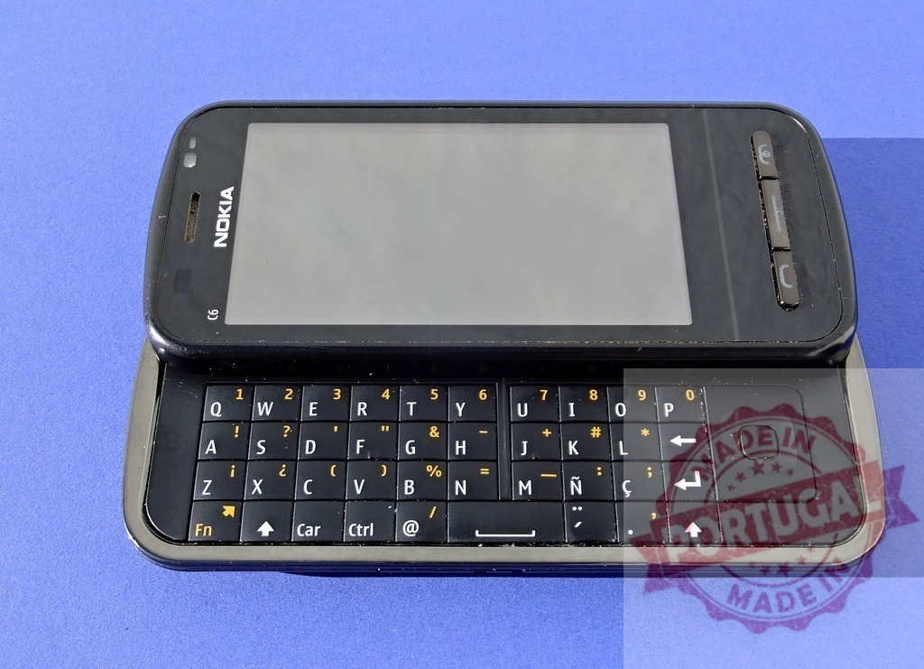 Nokia C6 smartphone showing blank touchscreen and qwerty keyboard | Old Nokia C6 mobile phone with sliding qwerty keyboard and blank touchscreen on blue background - Realized with Pictrs.com