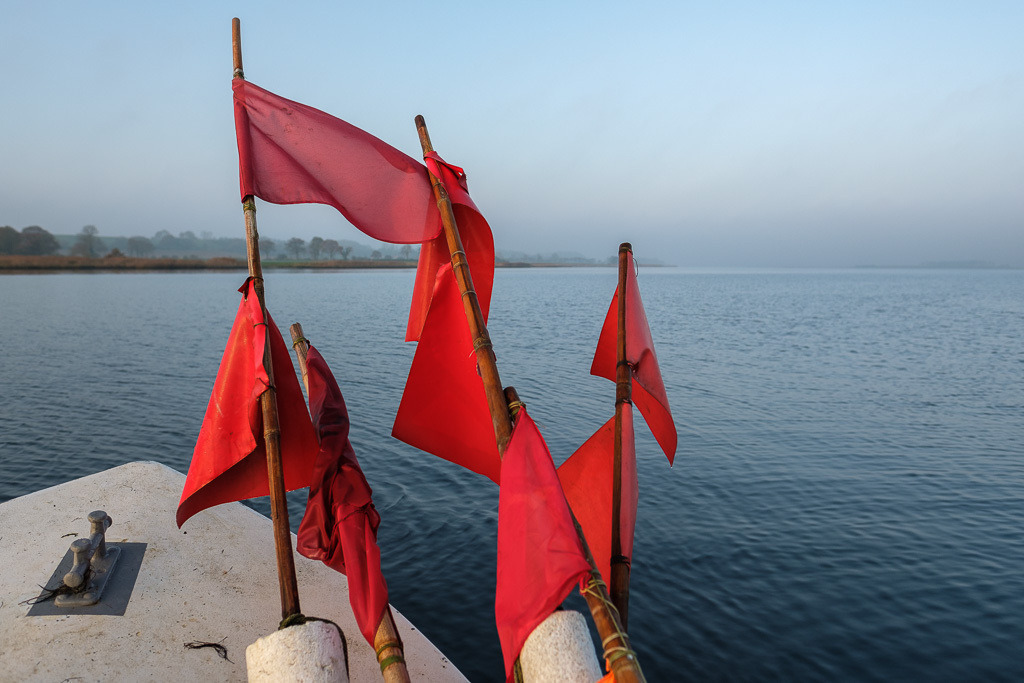 zeitenwende-farbe-03-16 | Matthias Nanz aus Schleswig ist einer der letzten Berufsfischer an der Schlei. Mit seinem Boot, vollgepackt mit Fanggeräten und Netzmarkierungen, fährt er vom Liegeplatz in Missunde zu den Fanggründen in der Schlei. Das Bild entstand am frühen Morgen Mitte November auf der Großen Breite der Schlei. - Realisiert mit Pictrs.com
