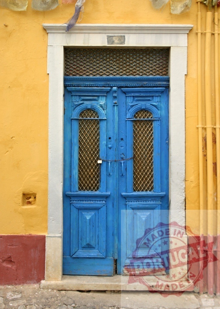 Old blue wooden door on yellow wall | Weathered blue door with metal grates in an ornate frame on a vibrant yellow building facade - Realisiert mit Pictrs.com